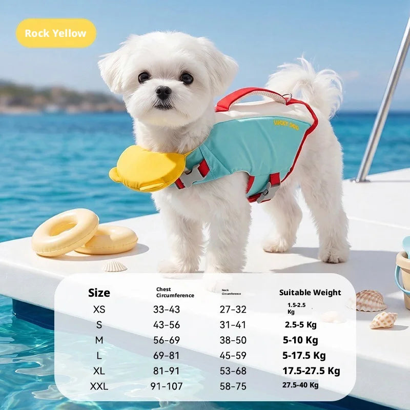 A small white dog standing on a boat wearing a light blue pet life jacket with red straps and a yellow belly float. The background shows blue ocean water and a sunny beach setting.