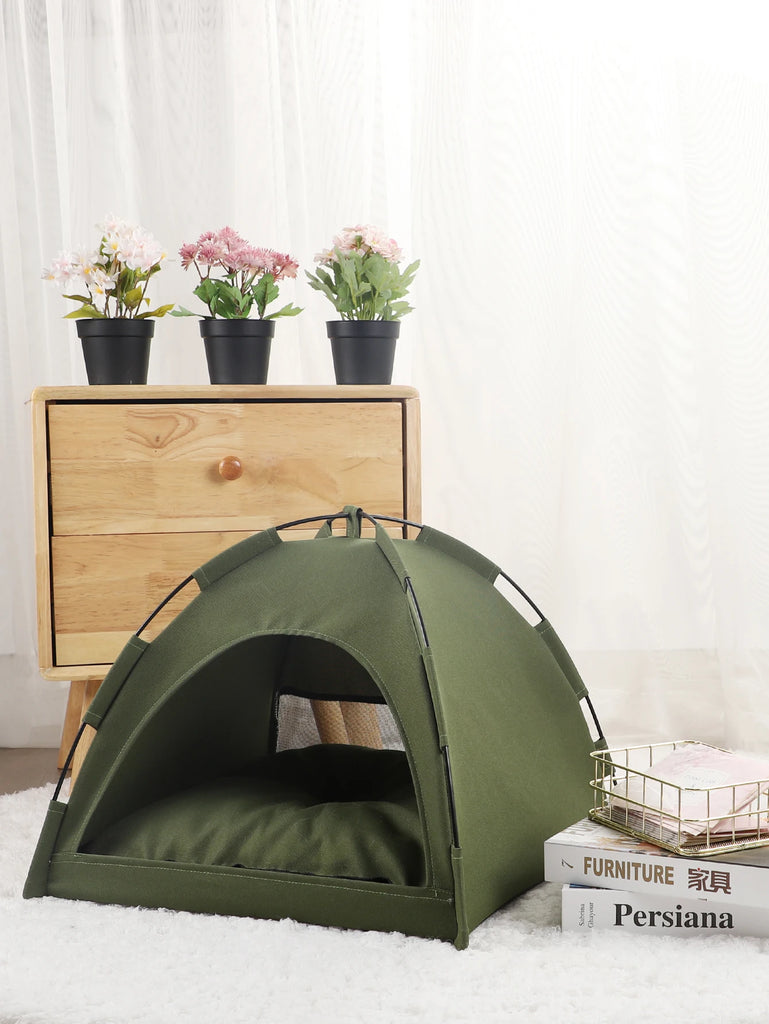 Green pet tent on a white surface with a wooden dresser and potted plants in the background.