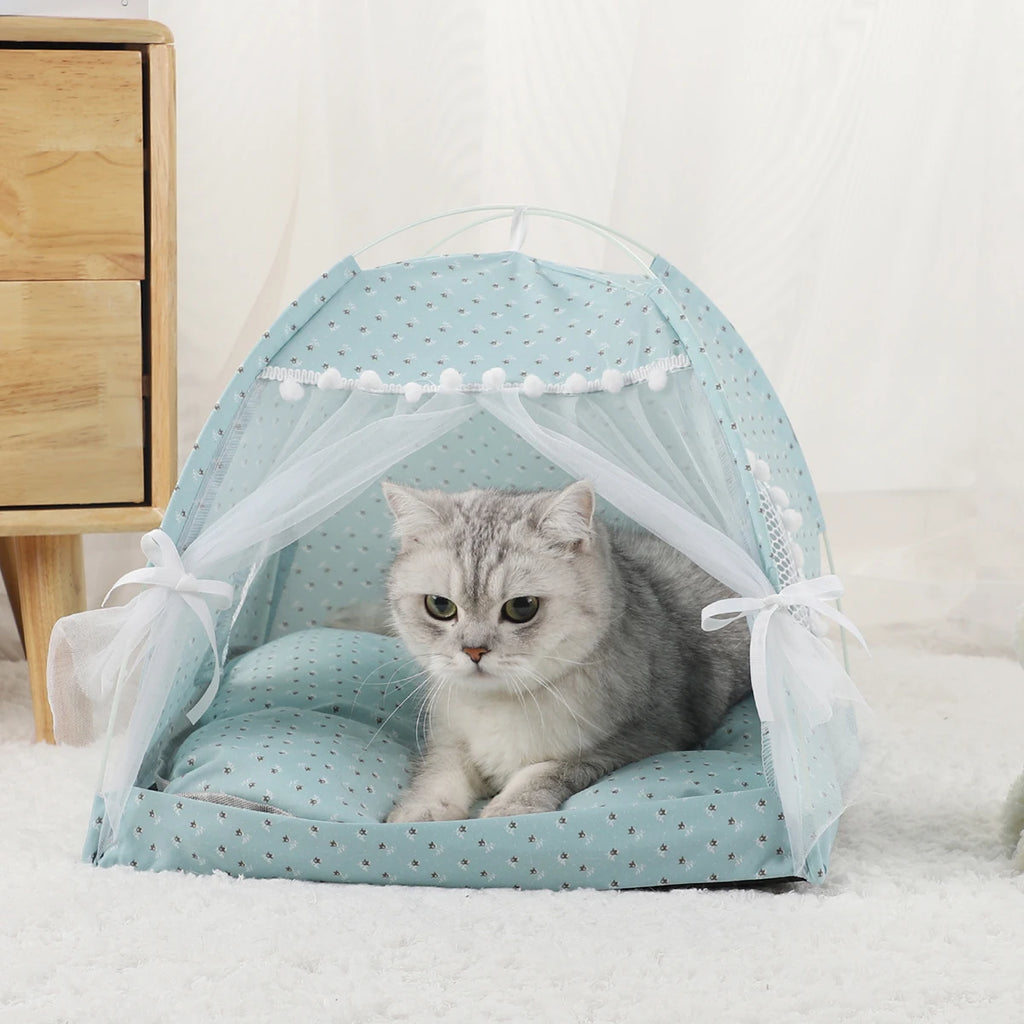 Cat lying inside a light blue pet tent with white polka dots on a white background