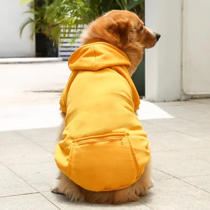 Dog wearing a yellow hoodie sitting on a tiled floor.