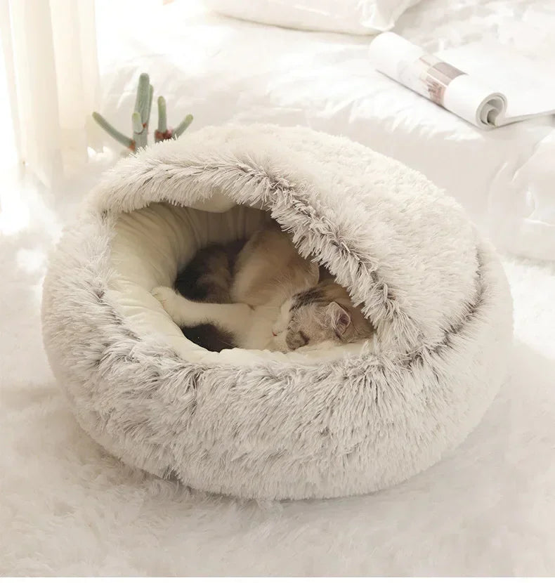 Fluffy white pet bed with a cat inside on a soft surface
