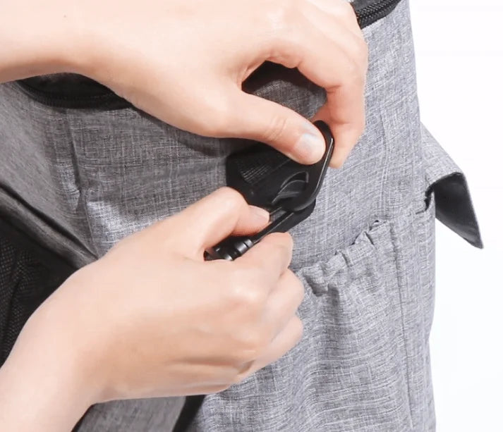 Person adjusting a gray garment with a black zipper on a white background