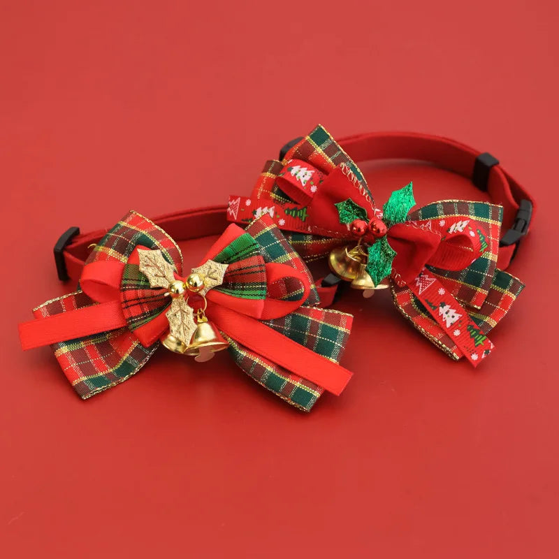 Two red pet collars decorated with large Christmas-themed ribbon bows, gold bells, and green holly accents, displayed on a solid red background.