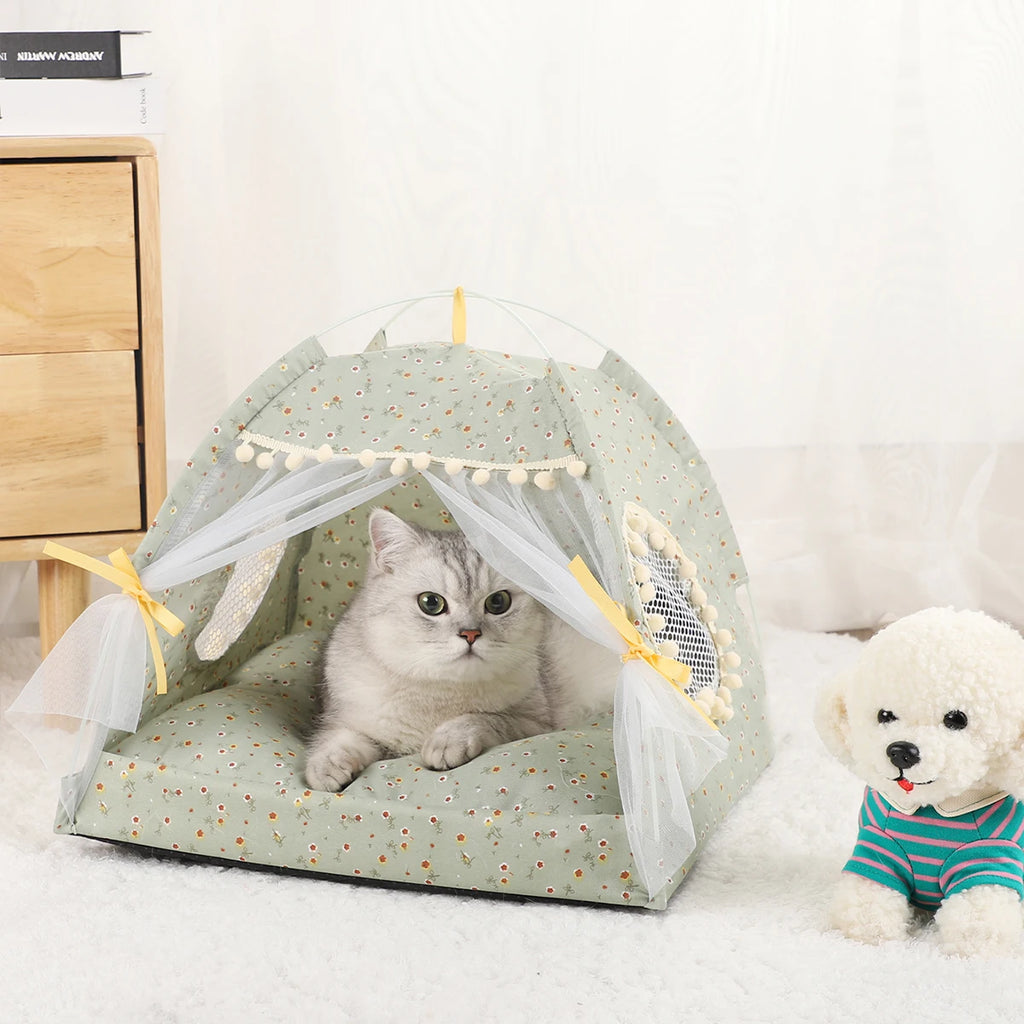 Cat inside a green pet tent with a white teddy bear wearing a striped shirt on a white surface.