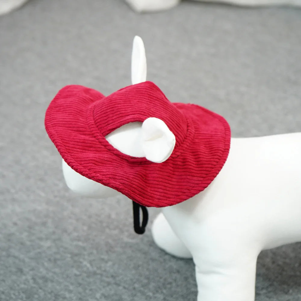 A red ribbed fabric pet hat with a white bow and black elastic strap, displayed on a white dog mannequin against a gray background.