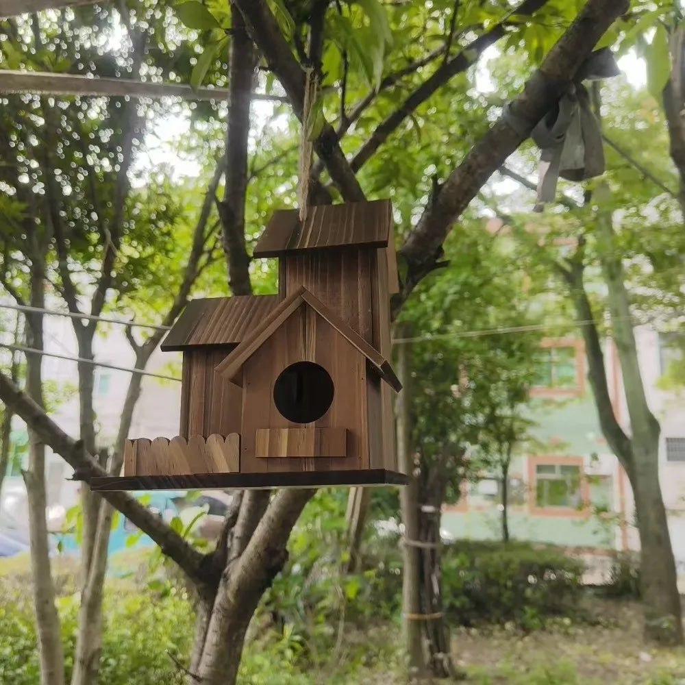Wooden birdhouse hanging from a tree branch in a garden setting
