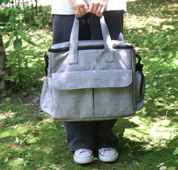 Person holding a gray bag outdoors on a grassy area