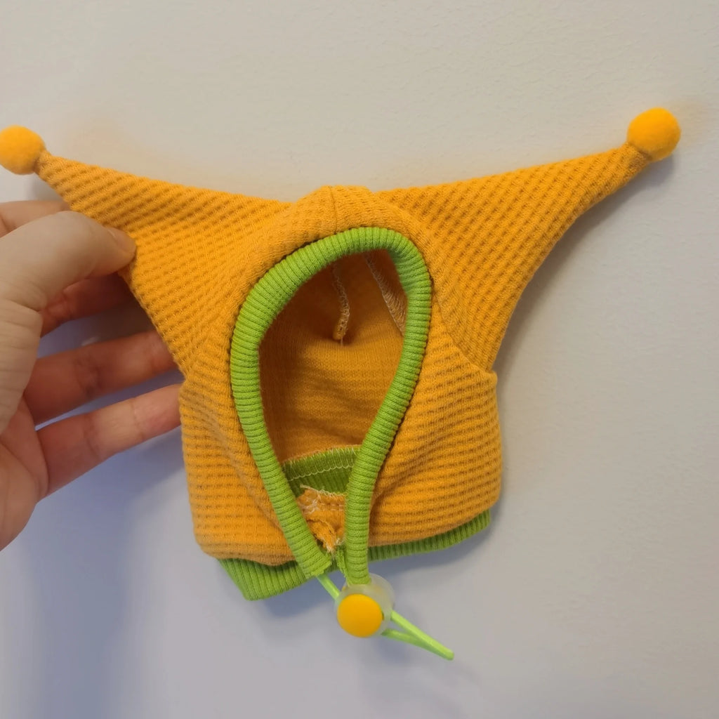 Yellow knitted pet toy with green trim and pom-poms on a white background