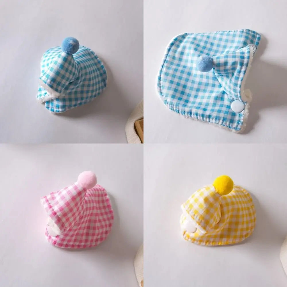 Four baby hats shown in a 2x2 grid on a light background, each in a different check pattern: light blue and white, pink and white, yellow and white, and light blue and white. Each hat has a small pom-pom on top and a white button closure.