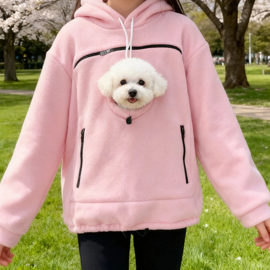 Person wearing a pink hoodie with a dog plushie in a park