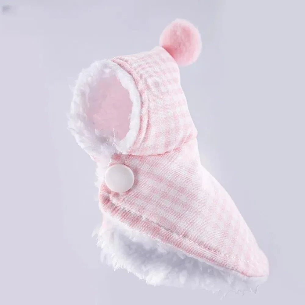A pink and white checkered pet hood with a fluffy white faux-fur trim and a matching pink pom-pom on top, shown against a light gray background.