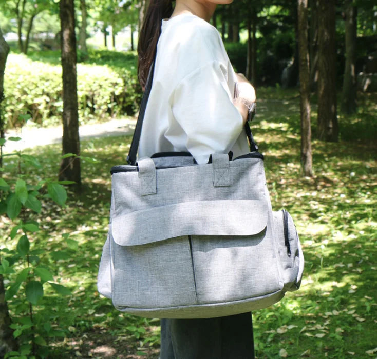 Person carrying a gray bag outdoors in a park