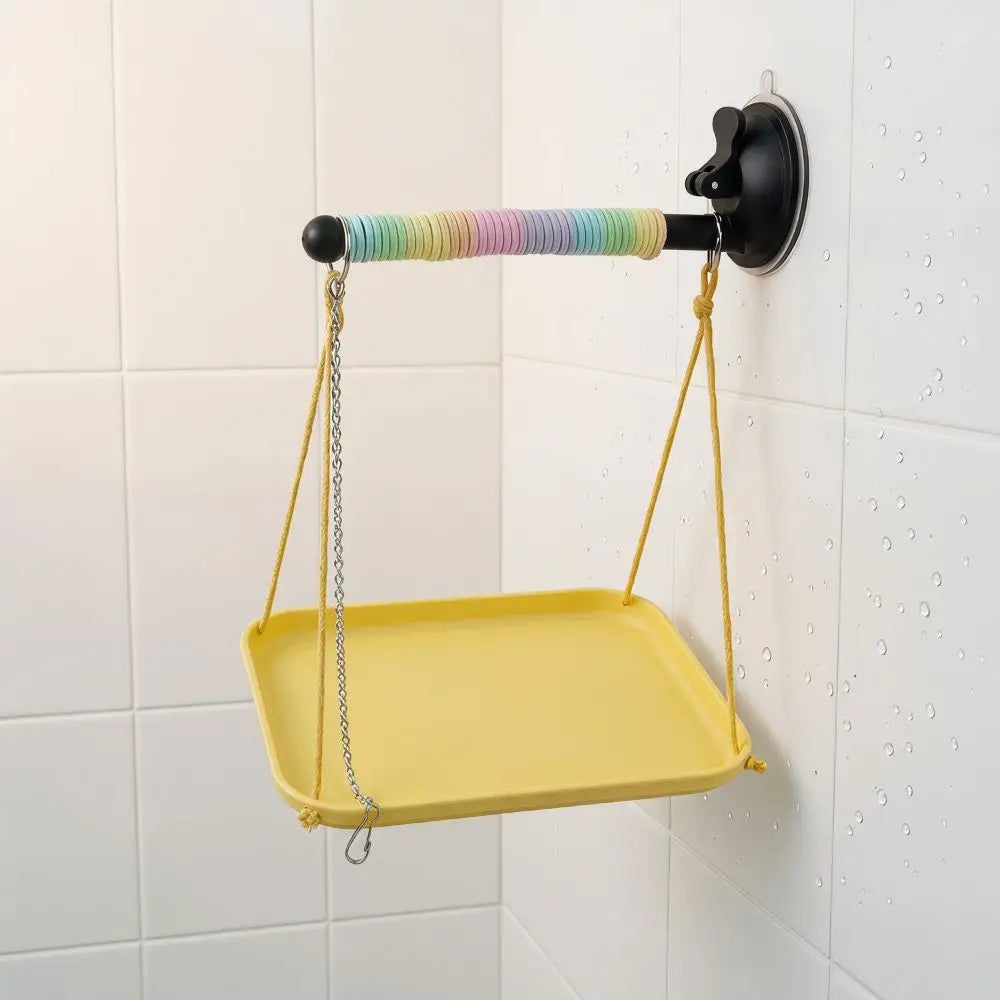 Yellow tray with a rainbow-colored handle attached to a wall bracket on a tiled wall.