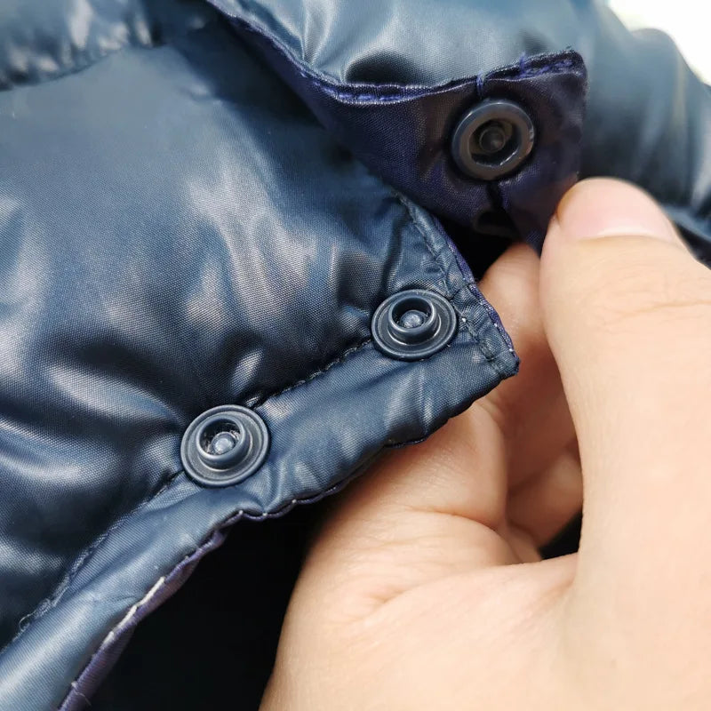 Hand holding a navy blue puffer jacket with buttons