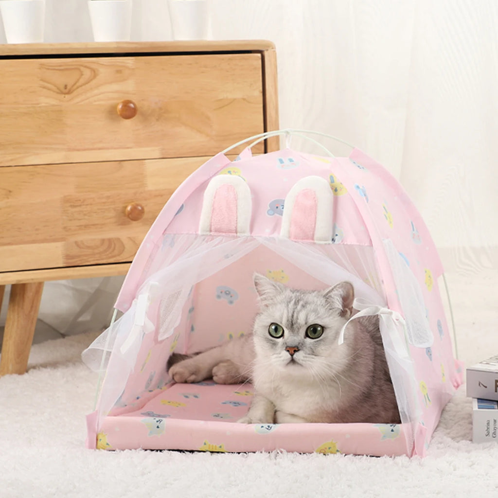 Cat inside a pink pet tent with bunny ears on a soft surface.