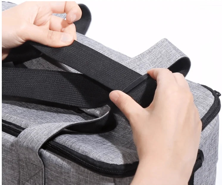 Person securing a black strap on a gray bag