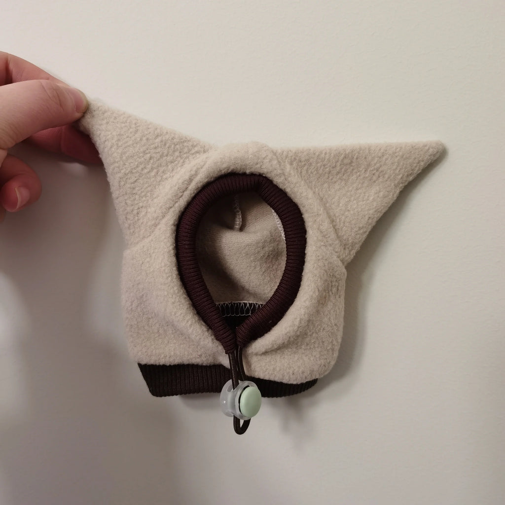Beige cat ear with brown trim held against a white background