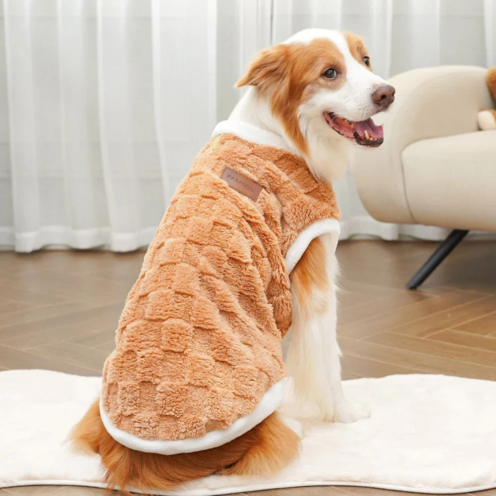Dog wearing a brown and white fleece coat sitting on a white blanket.