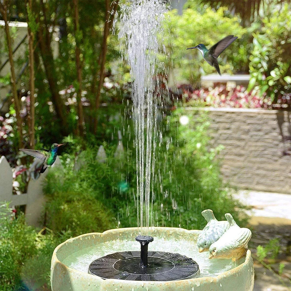 Solar fountain with water feature in a garden setting with hummingbirds.