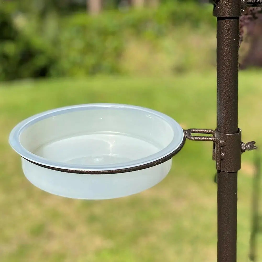Clear plastic bowl attached to a metal stand outdoors with greenery in the background