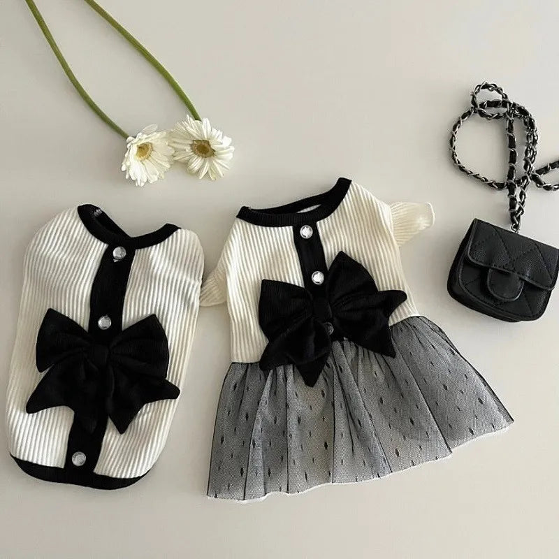 Children's outfit with black bows and a small handbag on a light background