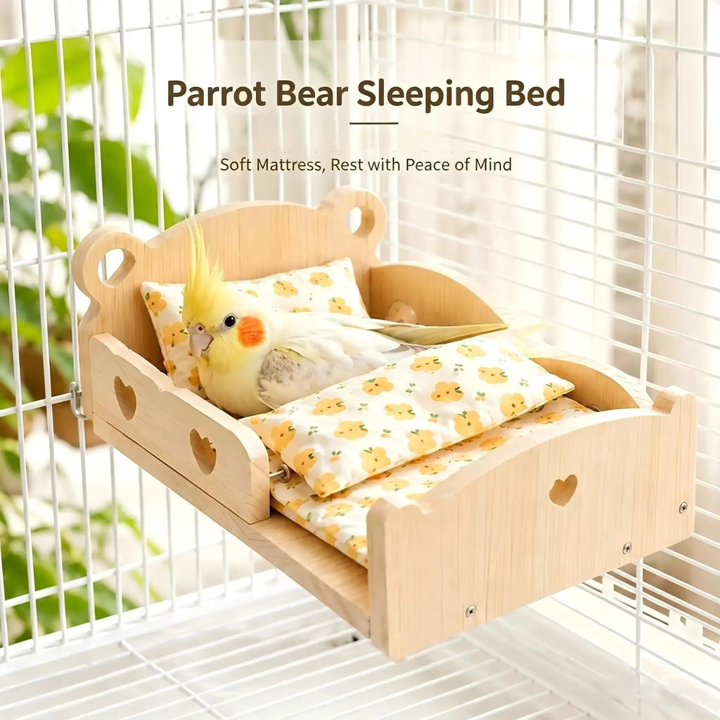 A wooden parrot sleeping bed mounted inside a white bird cage, with a yellow-and-white cockatoo lying on patterned mattress pads. Text at the top reads 'Parrot Bear Sleeping Bed' and 'Soft Mattress, Rest with Peace of Mind.