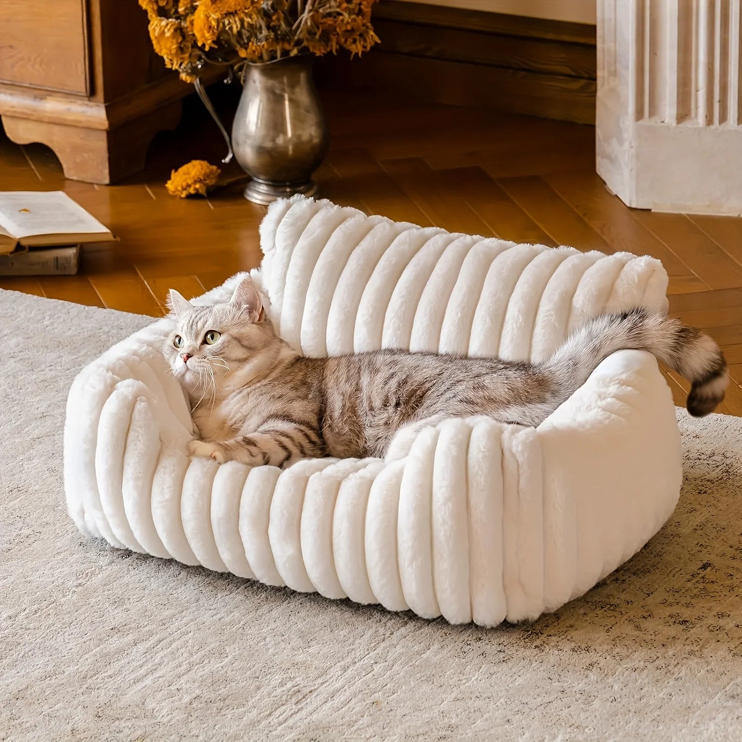 Cat lying on a plush white pet bed in a cozy room.
