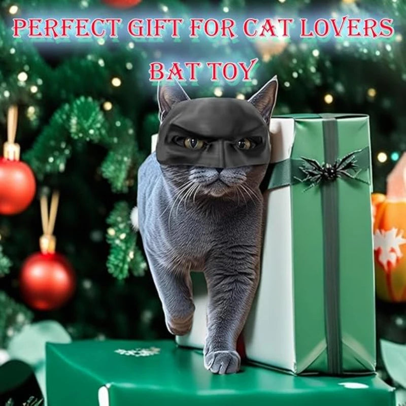 Cat wearing a bat costume with a green gift box against a Christmas tree background