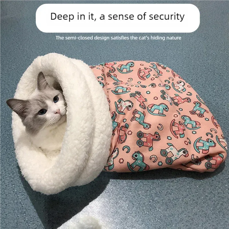 Cat snuggled in a white cozy cave with a pink blanket featuring toy patterns on a gray background.