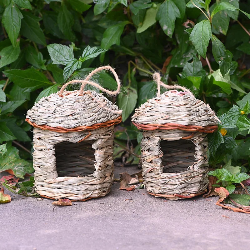 Two woven birdhouses on a ground with green leaves in the background
