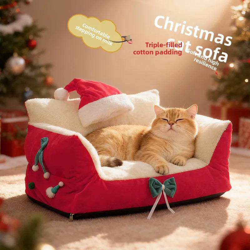 A ginger cat lies in a red and cream Christmas-themed pet sofa bed with a Santa hat, set in a warm holiday room with a decorated Christmas tree in the background.