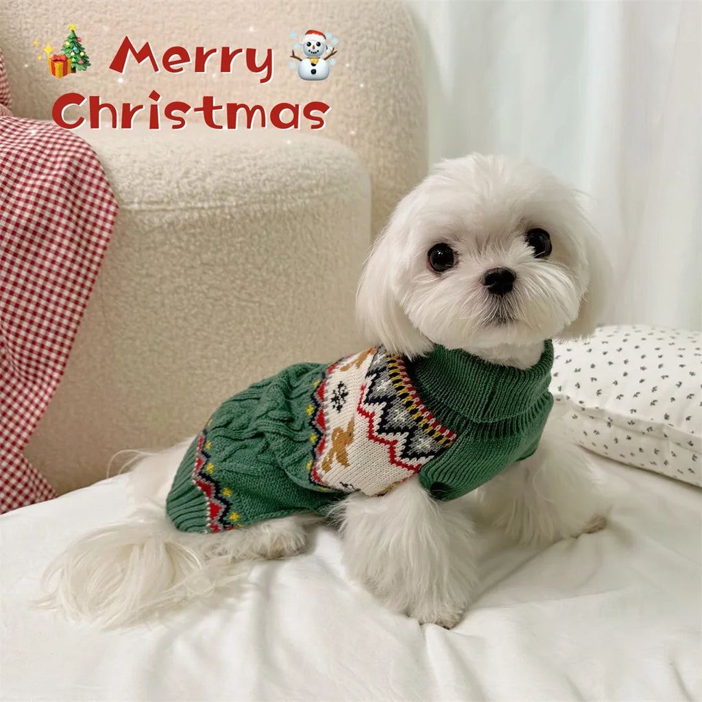 Small white dog wearing a green sweater with Christmas patterns, sitting on a couch with 'Merry Christmas' text and decorations.