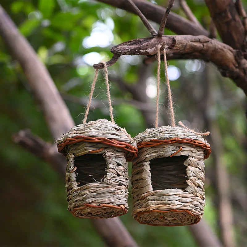 Two woven birdhouses hanging from a branch with a natural background