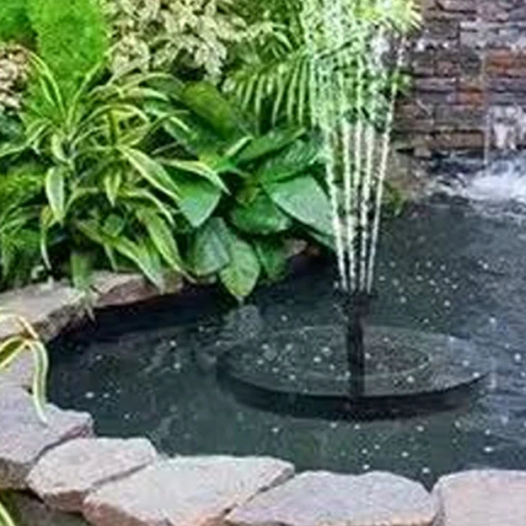 Small pond with a water fountain surrounded by greenery and stones.