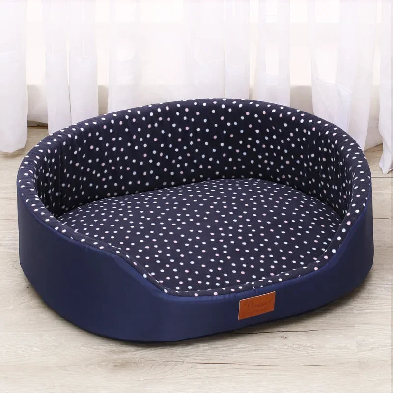 Navy blue pet bed with white polka dots on a light wooden floor.