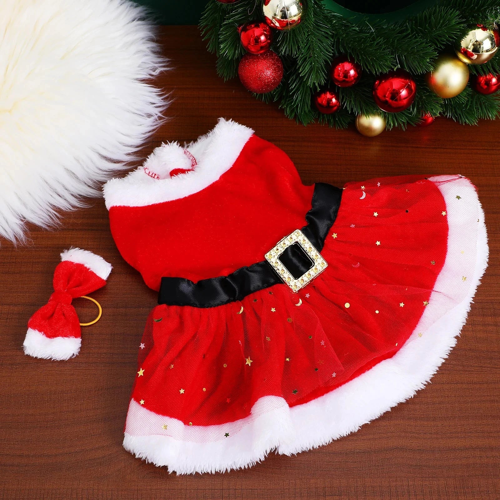 Red Santa Claus costume with black belt and white fur trim on a wooden surface.